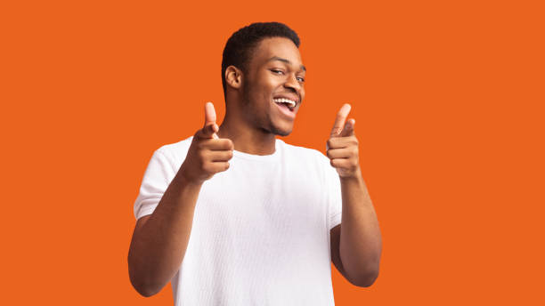 istock Happy afro guy choosing you over orange background 1201217239