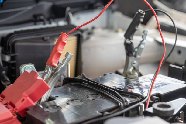 Charging car battery with electricity through jumper cables.
