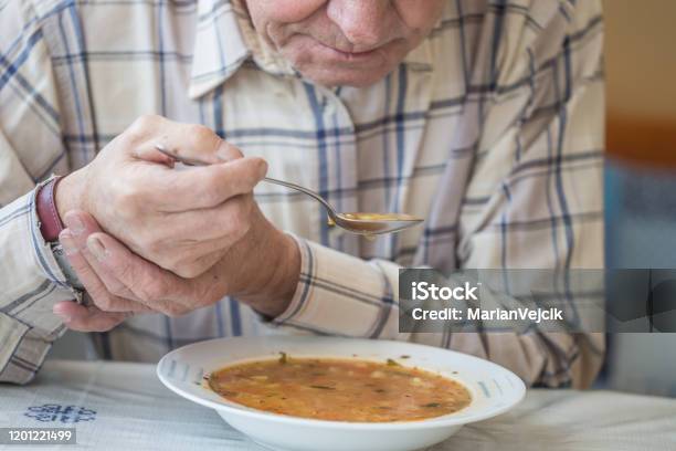 Elderly Man With Parkinsons Disease Holds Spoon In Both Hands Stock Photo - Download Image Now