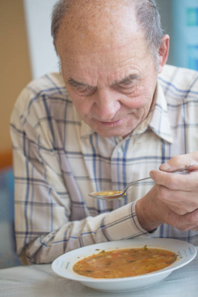 istock Elderly man with Parkinsons disease holds spoon in both hands. 1201221509