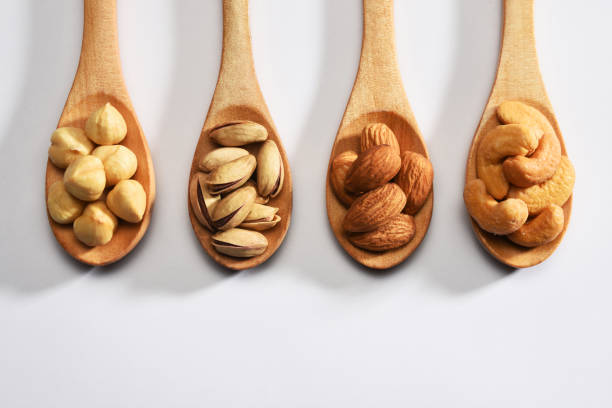 avellanas, almendras, pistachos y anacardos en las cucharas de madera sobre fondo blanco - 4679 fotografías e imágenes de stock