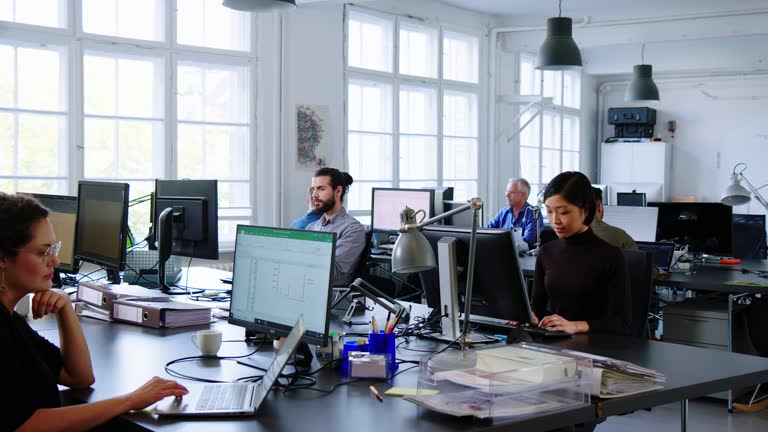 Creative business team working in a busy open plan office.Busy office with workers at desks working.