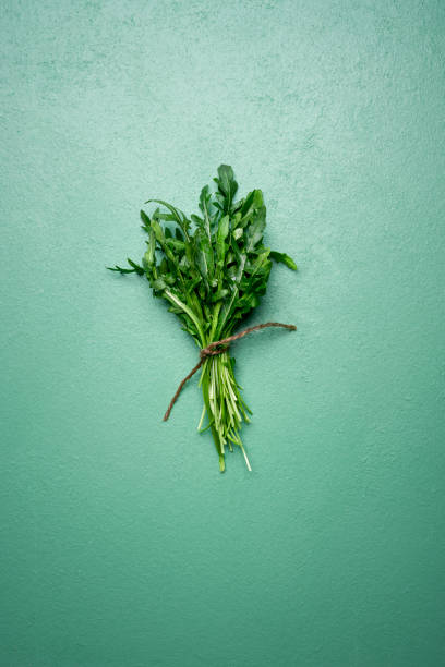istock Fresh arugula leaves in a bouquet on green table. Arugula bundle 1201237528