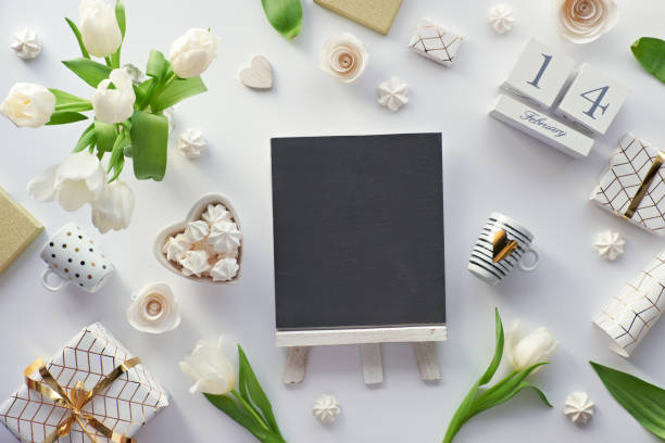 istock Spring flat lay, top view with white tulips, flowers, geometric decorations - coffee cups, gift boxes wrapped in hexagon paper with gold line pattern, stone blackboard, chalk board with copy-space. 1201237821
