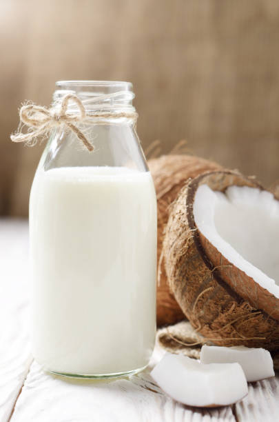 istock Glass bottle with milk or yogurt on white wooden kitchen table with coconut aside 1201237976
