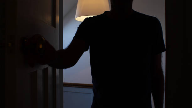 Silhouette of a man opening a door to a dark room. Silhouette of a man opening a door to a interior dark room, possibly a bedroom. He is an unrecognisable figure outlined be the landing light behind him. harassment photos stock pictures, royalty-free photos & images