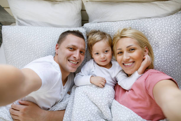 istock Happy family lying in bed and taking Selfie 1201248463