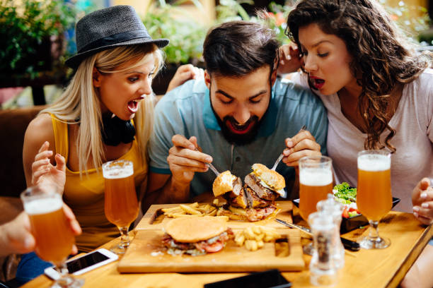 istock Young man eating oversized burger in a fast food restaurant 1201249618