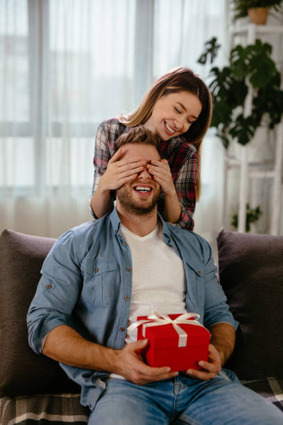 istock Young woman surprising her boyfriend with gift 1201250599