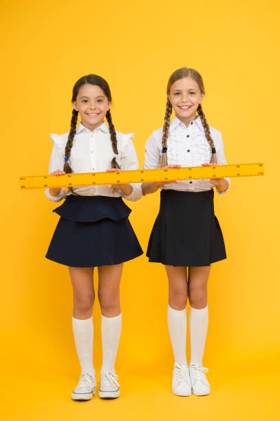 istock true friendship formula. school friendship. happy small girls study mathematics. students use yellow ruler. stem disciplines. back to school. Maths and geometry. Kids in uniform measuring 1201251381