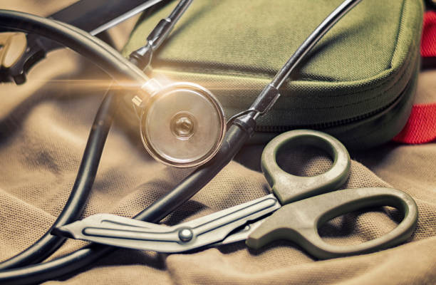 istock Stethoscope lies on a military uniform with scissors and a first-aid kit. The concept of health care, military insurance, state care. Top view. 1201254866