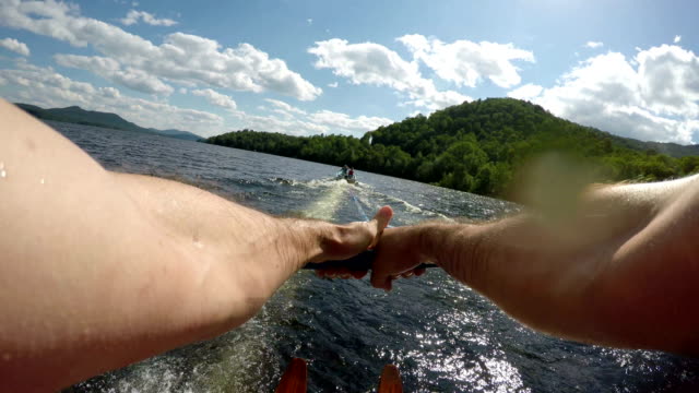 POV of a strong athletic man water skiing on a lake with wooden water skis