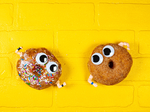 Donuts cartoon duel brawl: two fancy donuts having a fist fight against the yellow brick wall.
