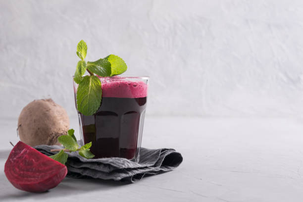 Glass of fresh beetroot juice garnish mint on grey. Glass of fresh beetroot juice garnish mint on grey table. Close up. beet stock pictures, royalty-free photos & images