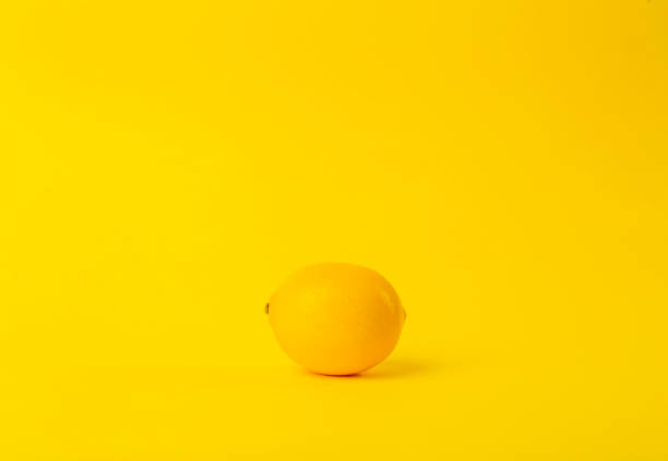 istock Summer and vitamins background. Lemon on a yellow background, minimal food concept 1201263232