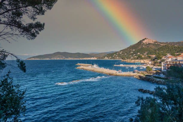 arcobaleno sul villaggio costiero del sud italia con il mar mediterraneo - rainbow harbor foto e immagini stock