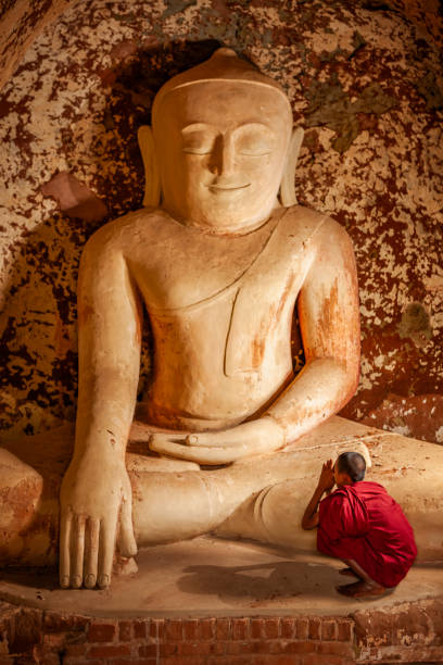 Two young buddhist monks praying inside an ancient temple, Bagan, Myanamar