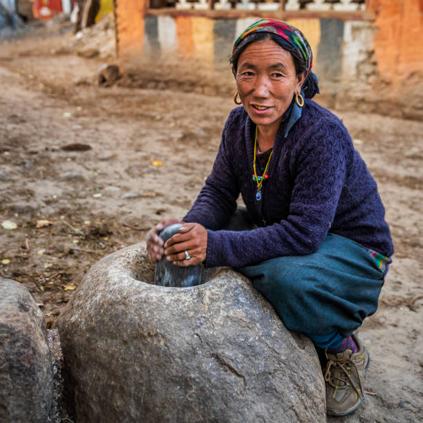 istock Tibetan woman using a stone mortar to make flour, Upper Mustang, Nepal 1201264897