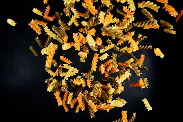 Uncooked pasta swirls on dark background macro photo