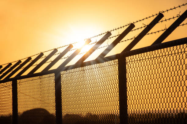 istock Sun rays over barb wire on metal fence, Sunset 1201272683