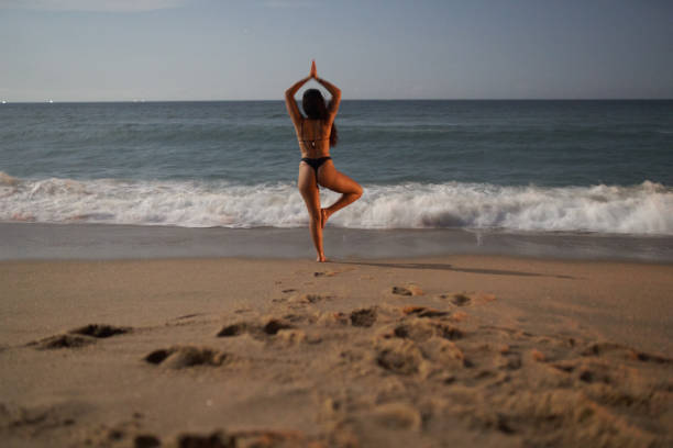 istock woman practicing yoga at the beach in the moonlight 1201273551