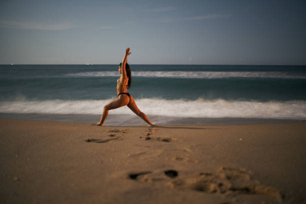 istock woman practicing yoga at the beach in the moonlight 1201273554