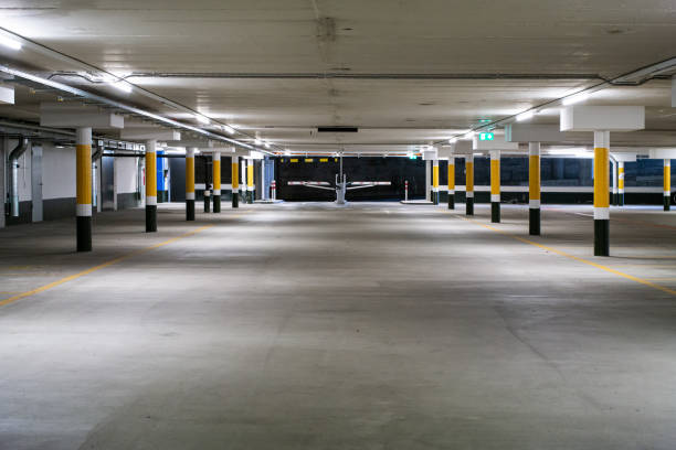istock Inside underground large empty parking lot with barrier entrance at night illuminated by neon light 1201274667