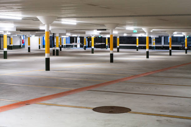 istock Inside underground large empty parking lot with barrier entrance at night illuminated by neon light 1201274678