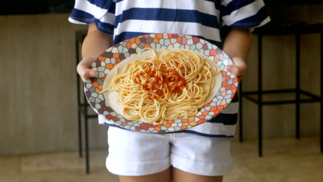 Close up of a young girl spilling a plate of spaghetti on the floor