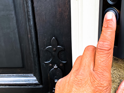 Black woman ringing doorbell.