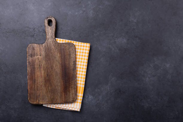 Cutting board and linen napkin on dark stone table. Copy space stock photo