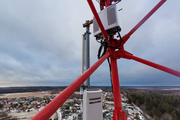 istock Top of red telecommunication tower with vertical panel antenna and remote radio unit, power and optic cables in winter day. 1201277353