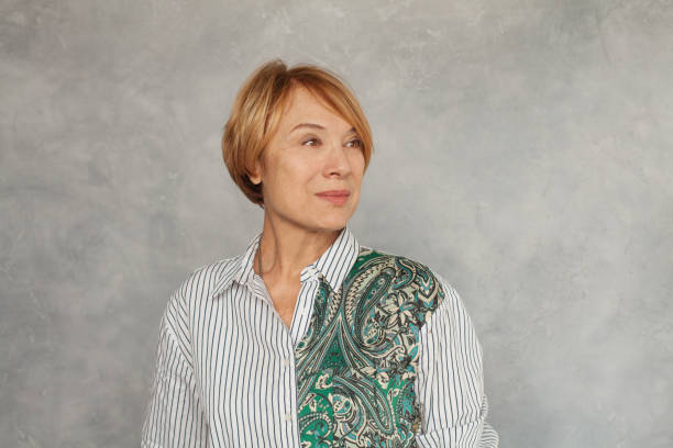 istock Mature woman looking aside on gray background 1201278517