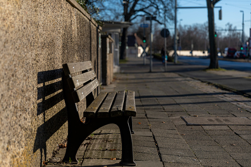 Empty bench waiting for users in bright winter sunshine in Brunswick, Germany.
