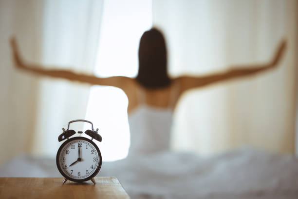 Woman stretching hands in bed after wake up, sun flare . Brunette entering a day happy and relaxed after good night sleep and back view. Concept of a new day and joyful weekend Woman stretching hands in bed after wake up, sun flare . Brunette entering a day happy and relaxed after good night sleep and back view. Concept of a new day and joyful weekend. smash alarm clock stock pictures, royalty-free photos & images
