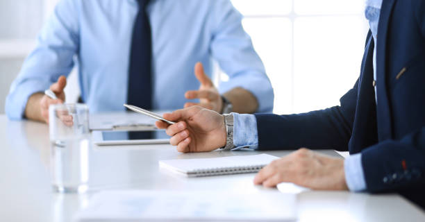 istock Two unknown businessmen or partners using tablet pc and discussing questions at meeting in modern office, close-up of hands. Group of managers at negotiation or brainstorm. Teamwork, partnership and business concept 1201282675