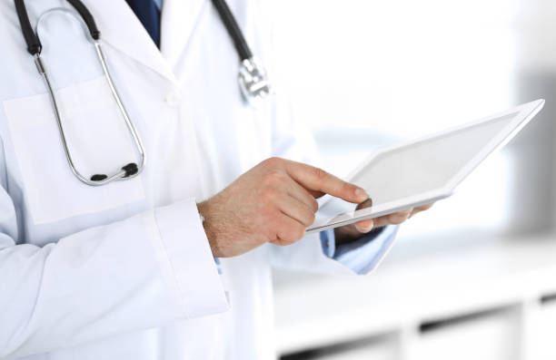 istock Doctor man using tablet computer for network research or virtual disease treatment, hands close-up. Perfect medical service in clinic. Modern medicine, medic data and healthcare concepts. Toned picture 1201282692