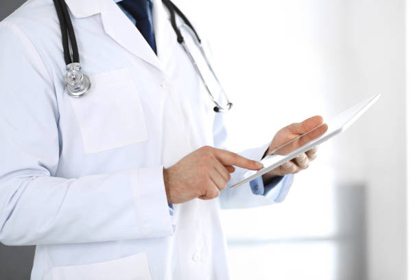 istock Doctor man using tablet computer for network research or virtual disease treatment, hands close-up. Perfect medical service in clinic. Modern medicine, medic data and healthcare concepts. Toned picture 1201282696