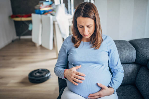 istock Pregnant woman resting while robot vacuum cleaner cleaning floor 1201285484