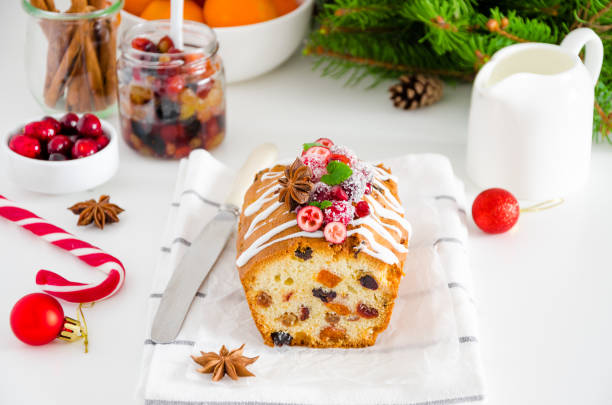 istock Traditional fruit cake with mixed fruit and cherries decorated with sugar icing, cranberries, pomegranate and cherry on a white background. Horizontal orientation. 1201285755