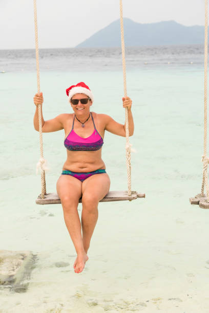 istock Pretty women in bikini on rope swing over the sea 1201286708
