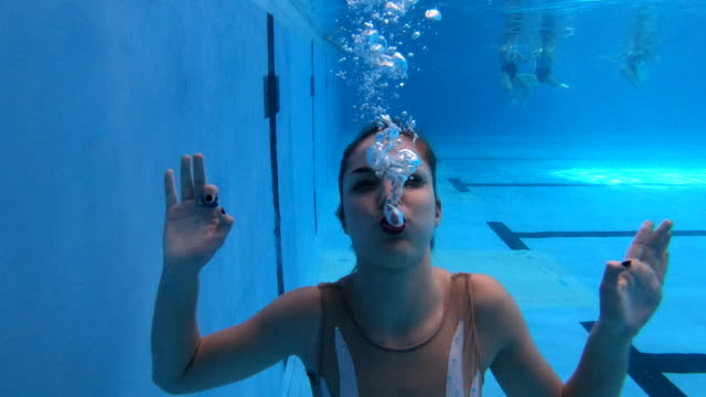 Front view video of a synchronized swimmer showing off her lung capacity