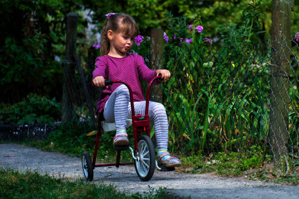 istock Little girl rides a retro tricycle 1201287408