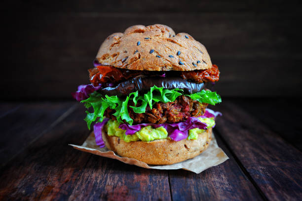 Fresh beetroot lentil vegan burger with grilled eggplant, sun-dried tomatoes, guacamole sauce and rye buns. Vegan food concept