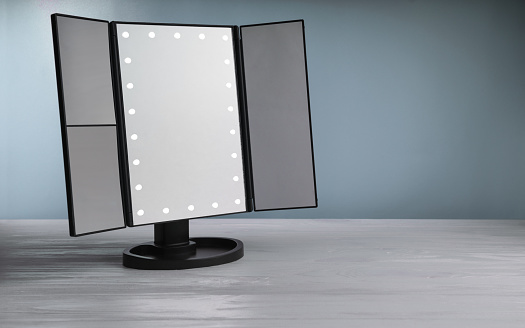 LED vanity Make up mirror on white table with blue background. Magnifying LED multiple mirrors