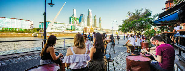 Hip young people enjoying a late afternoon drink in Puerto Madero Hip young people enjoying a late afternoon drink in Puerto Madero panorama. Puente de la mujer in the background. puente de la mujer stock pictures, royalty-free photos & images