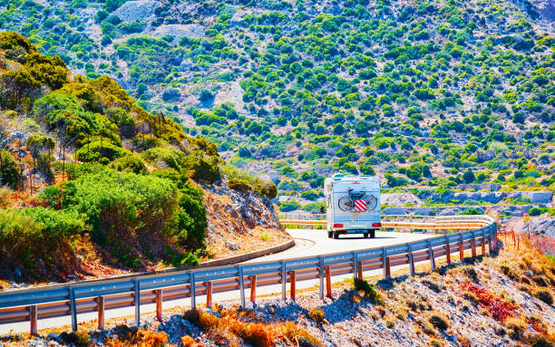 Caravan on road at Buggerru in Carbonia Iglesias Sardinia reflex Camper with bicycle on road at Buggerru in Carbonia-Iglesias in Sardinia Island, Italy summer. Caravan motorhome on holidays at highway. Minivan rv on motorway. Cagliari province. Mixed media. Buggerru stock pictures, royalty-free photos & images