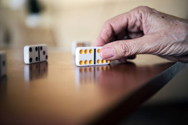 A close-up view of a retired senior woman who is playing domino games at home with his husband. An older senior couple is playing a board game in the living room of their apartment.