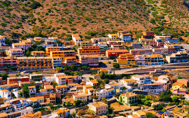 Cityscape of Buggerru city with houses architecture at hills reflex Cityscape with Buggerru city with cottage house architecture at the Mediterranean Sea in South Sardinia in Italy. Sardinian Italian small town in Sardegna. Buggerru stock pictures, royalty-free photos & images