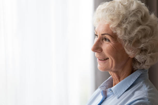 istock Close up happy smiling woman looking out window, dreaming alone 1201295556